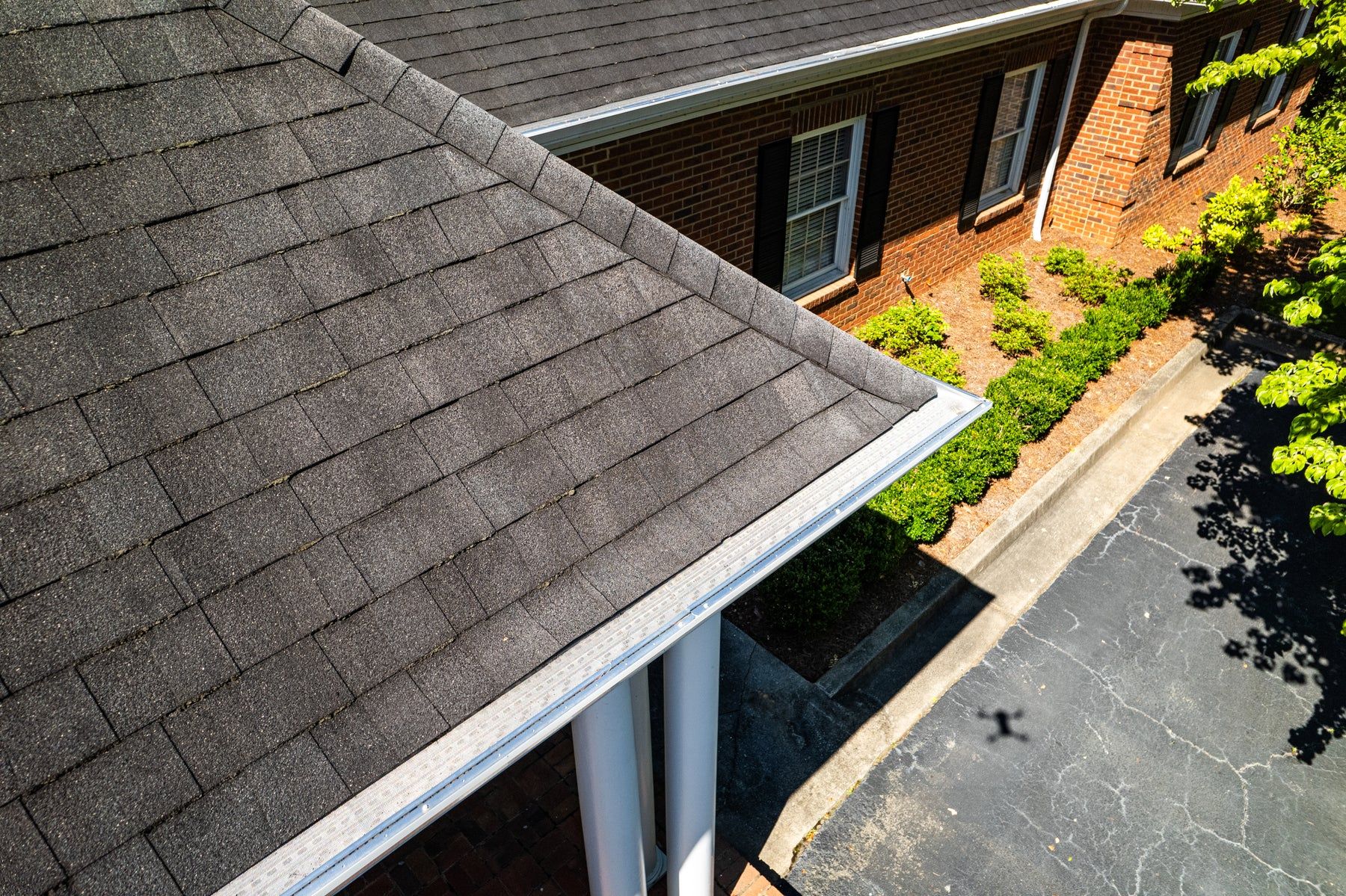 White gutters with guards along a shingle roof